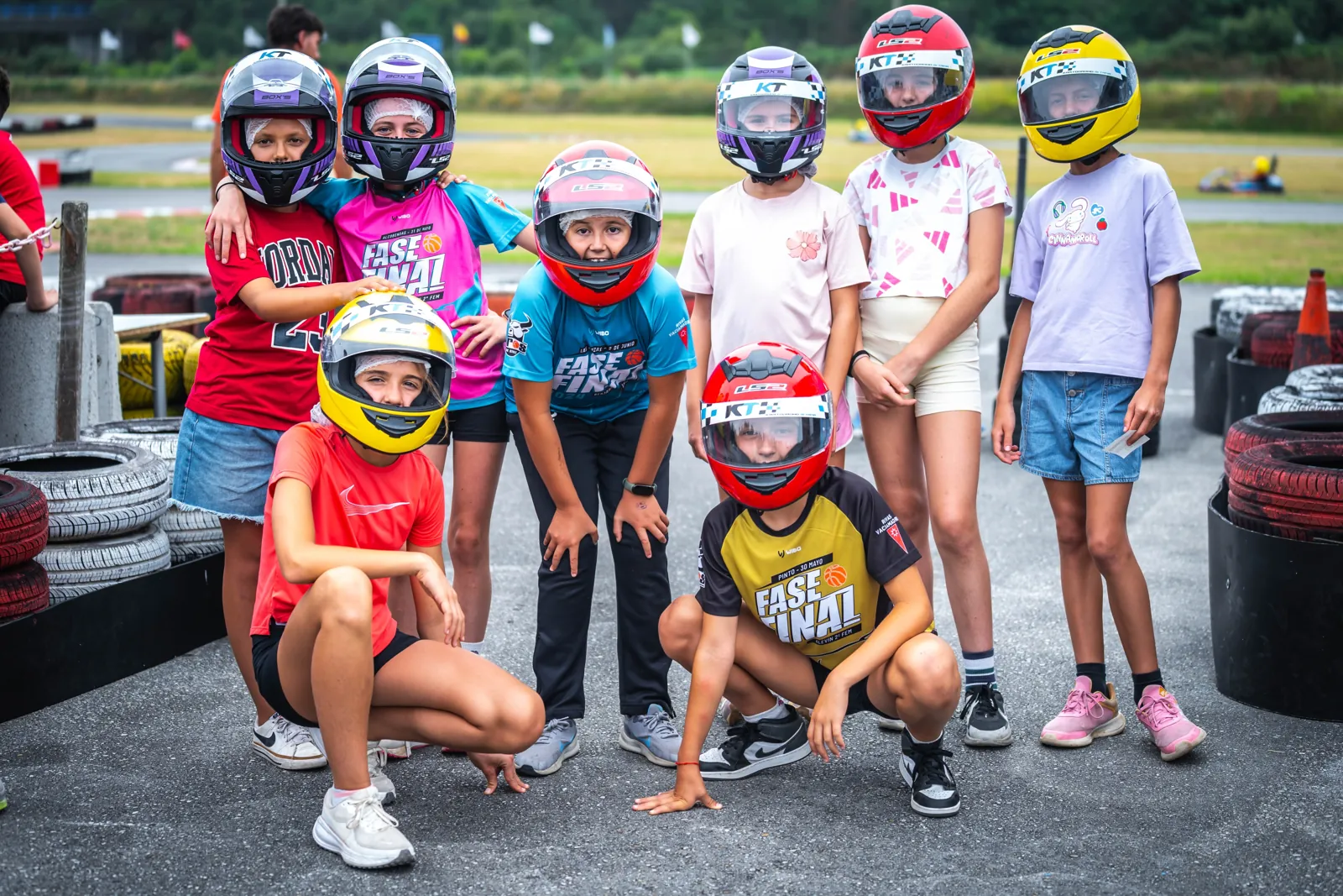 Participantes con casco posando en el circuito de karts