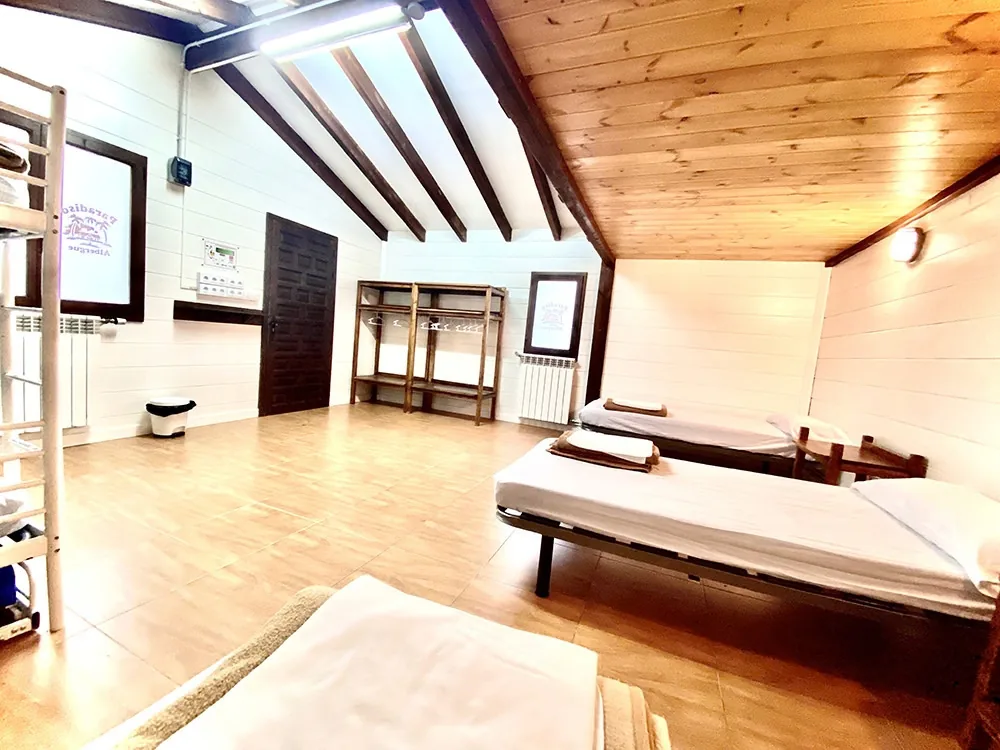 Habitación del Albergue Paradiso con camas y techo de madera